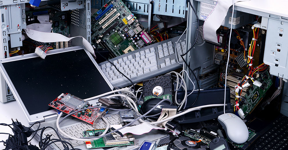 Stacks of old computers and other IT hardware symbolizing the disorganization that fuels the IT e-waste crisis.